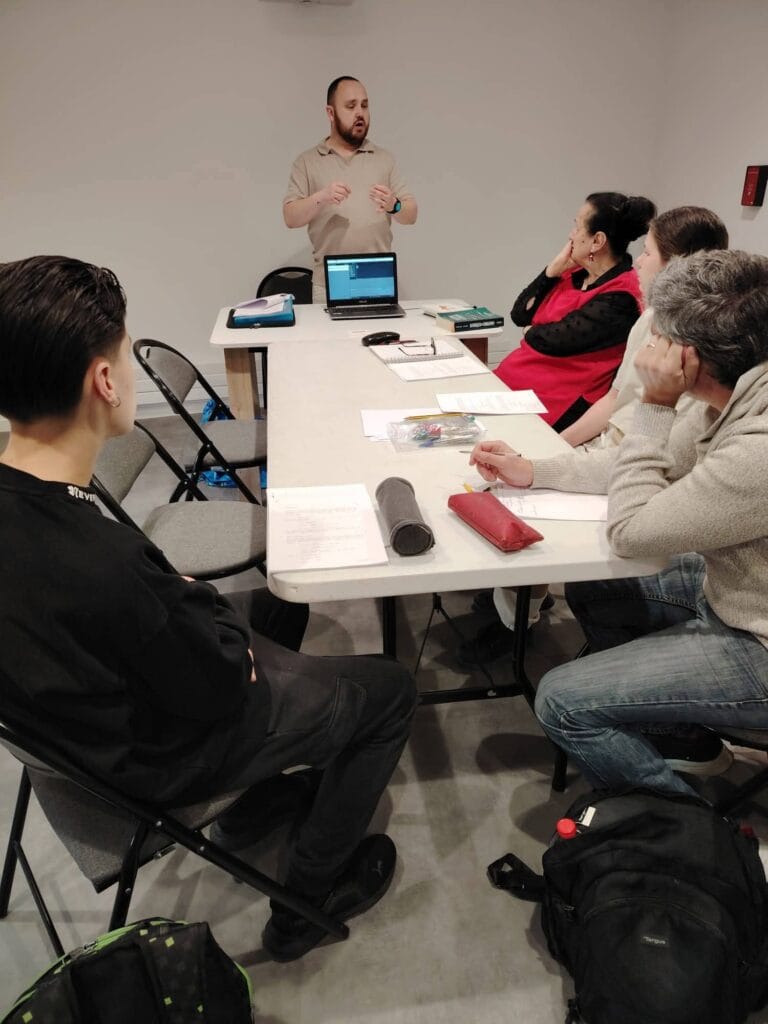 Un formateur anime un atelier décriture de scénario avec un groupe de participants assis autour dune table de travail