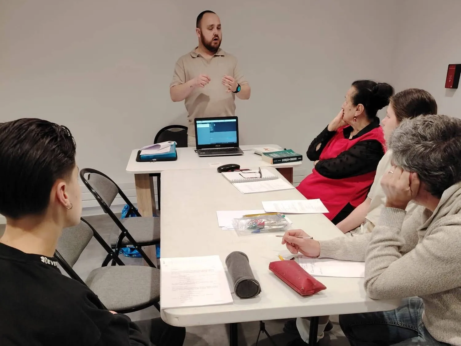 Un formateur anime un atelier décriture de scénario avec un groupe de participants assis autour dune table de travail