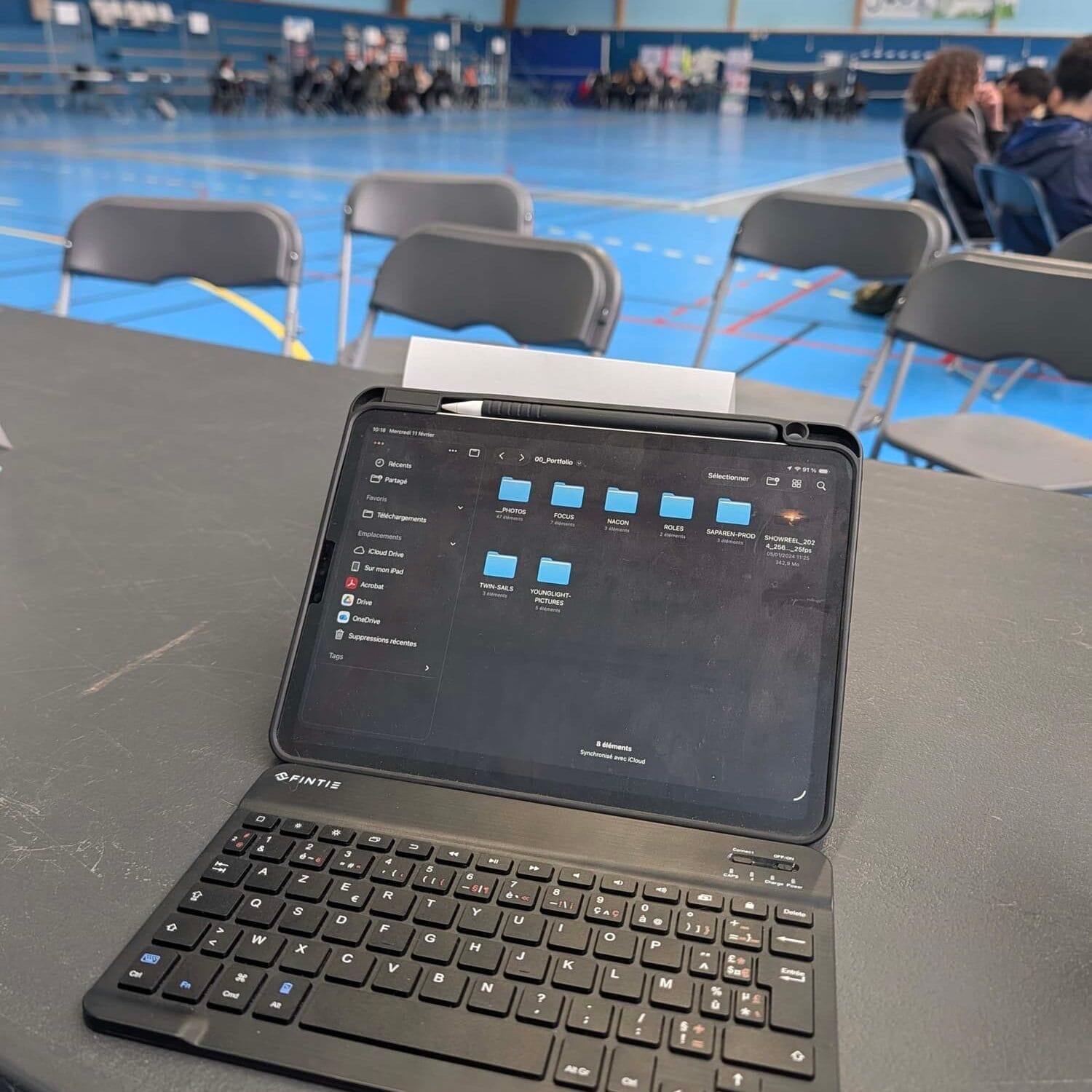 forumjouylemoutier01 | Saparen Prod Ordinateur portable posé sur une table lors du Forum de Jouy le Moutier avec une salle sportive et des participants en arrière plan
