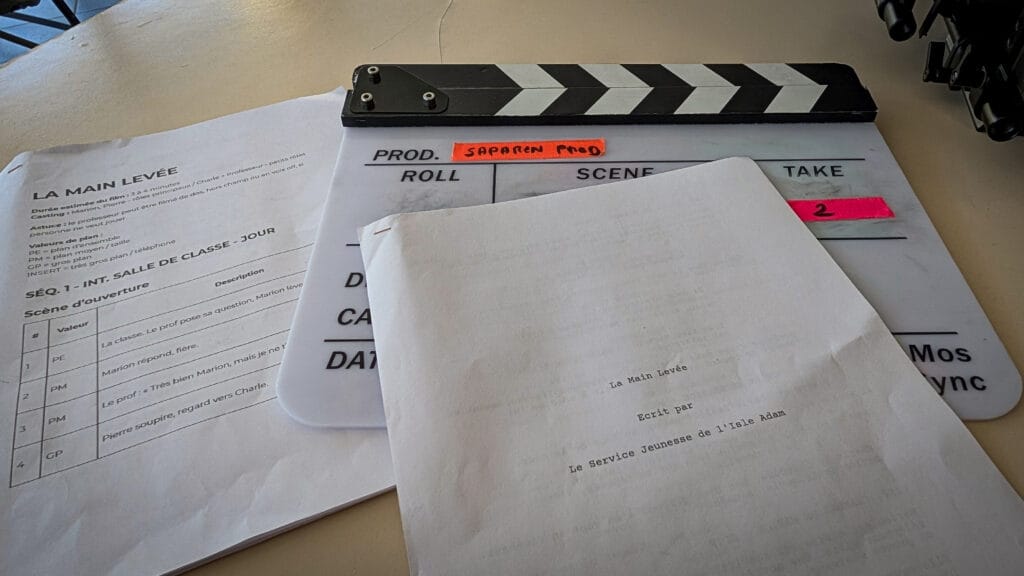 Clapboard resting on a desk with script pages and notes visible in Frenchwork documents beneath it